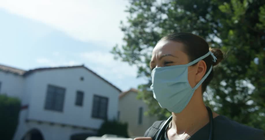A female nurse walks down a neighborhood street