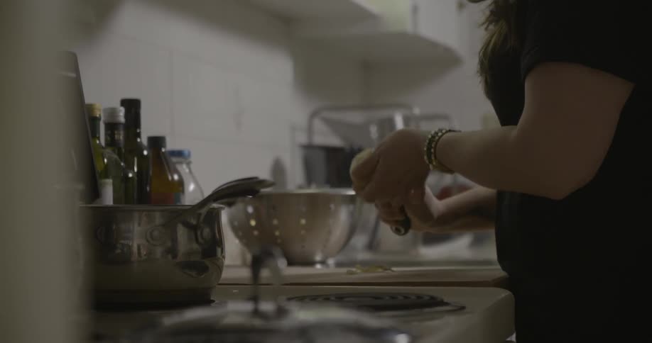 A woman peels a potato in a kitchen