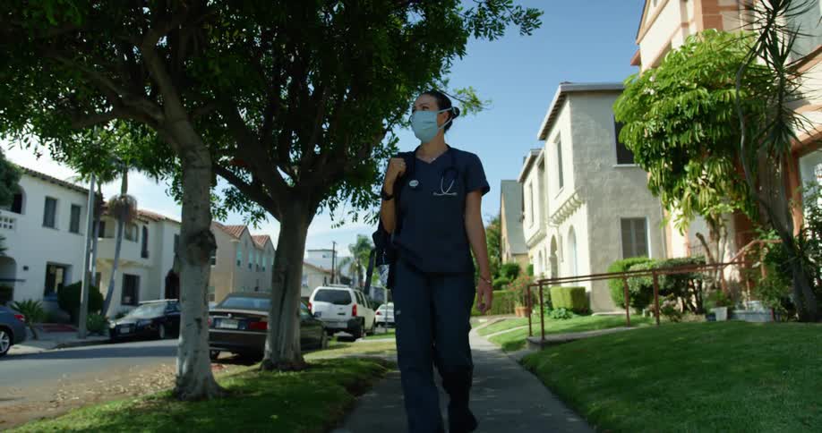 A nurse walks on the sidewalk