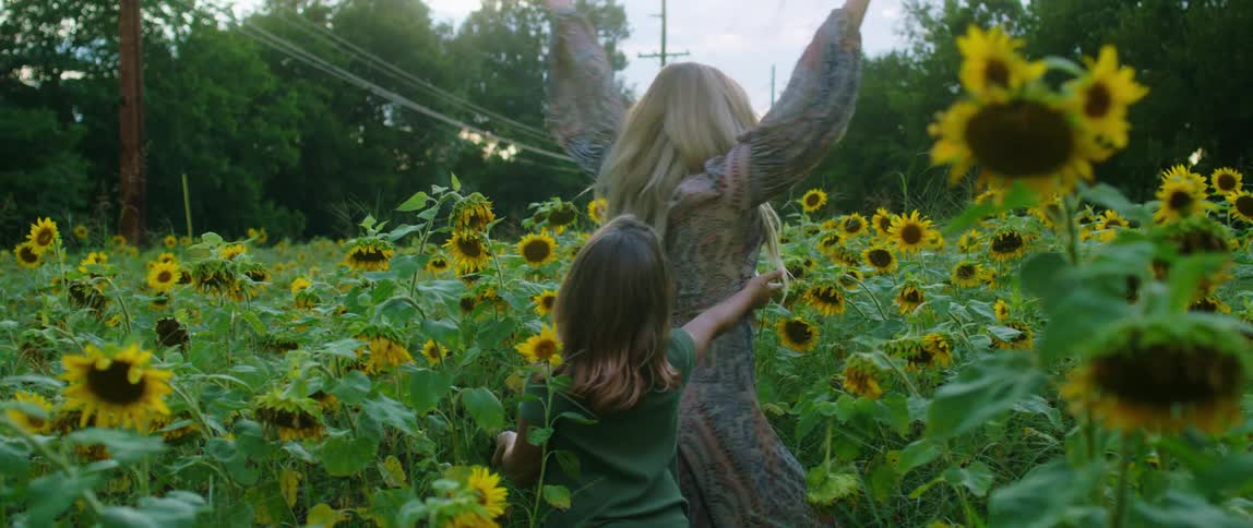 A mother and daughter dance in the sunflower patch