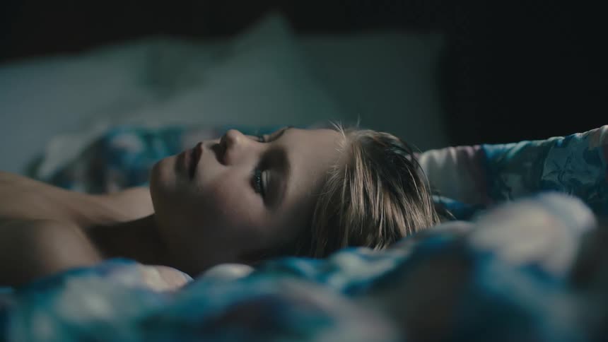 A boy laying in bed with a blanket and pillows looking up