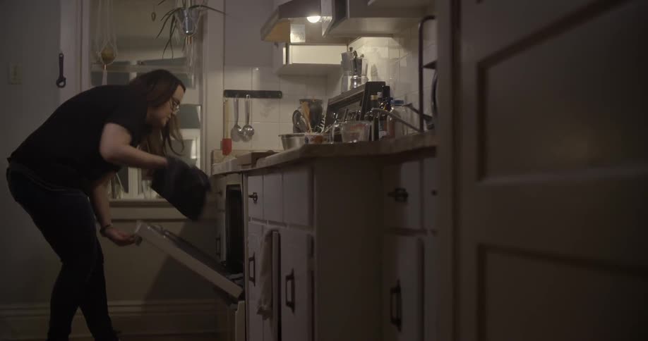 A woman places a pan in the oven