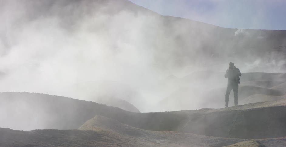 A man walks near a hole in the ground emitting steam