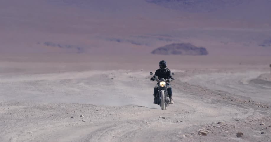 A motorcyclist rides a bike through a desert
