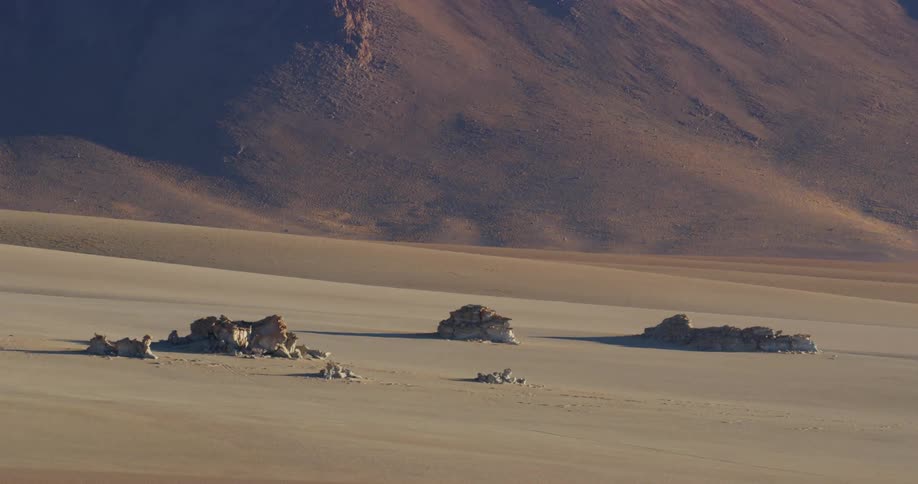 A group of rock formations at the base of a mountain in the desert during the day