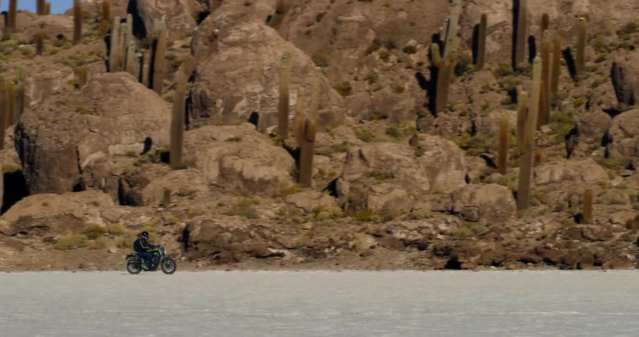A person driving their motorcycle on the shore