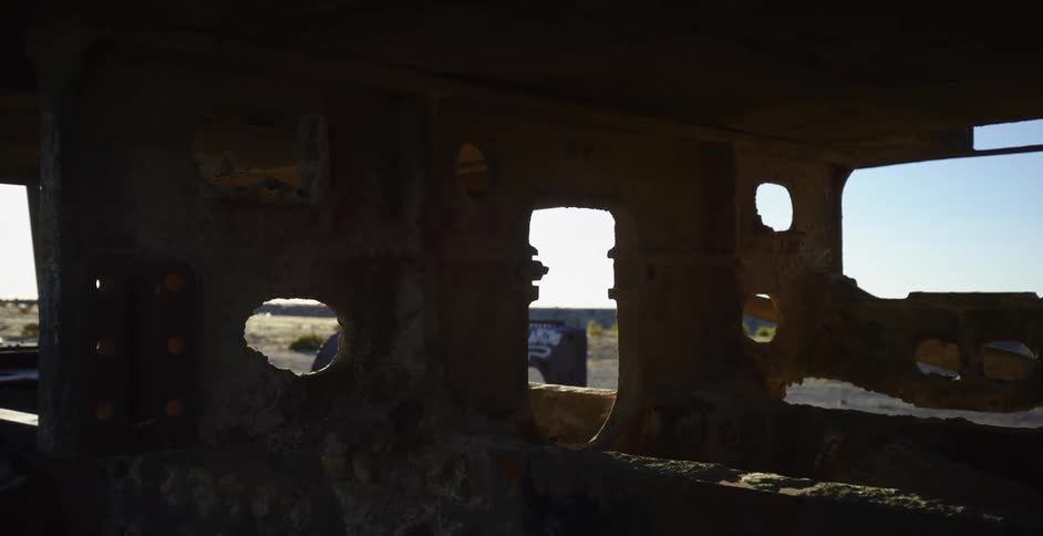 Looking out of a rusted metal building at the desert