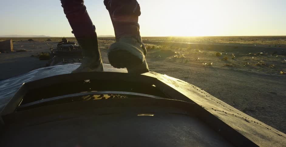 A person with boots walking on metal with the sky in the background