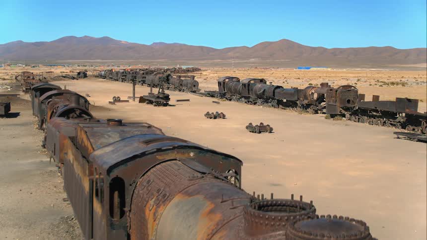 A rusted and burnt out train sitting in the desert