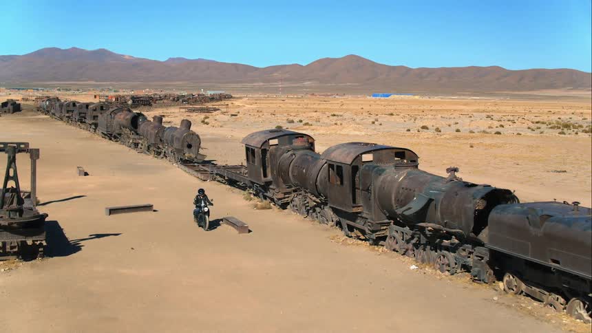 A person driving their motorcycle next to an abandoned old train