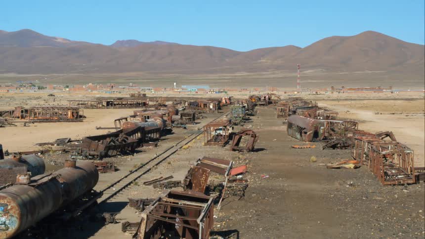 An abandoned railway with rusted destroyed train cars lying all about