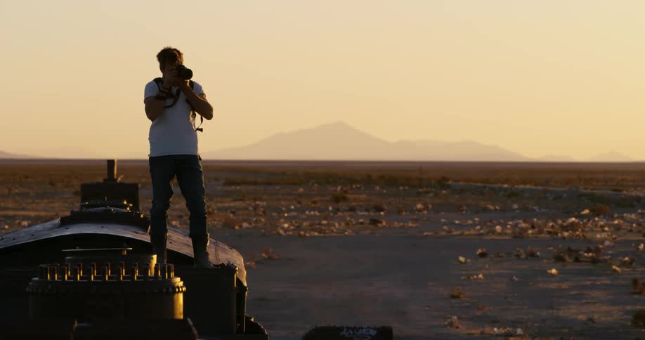 A man standing on top of an old train takes pictures