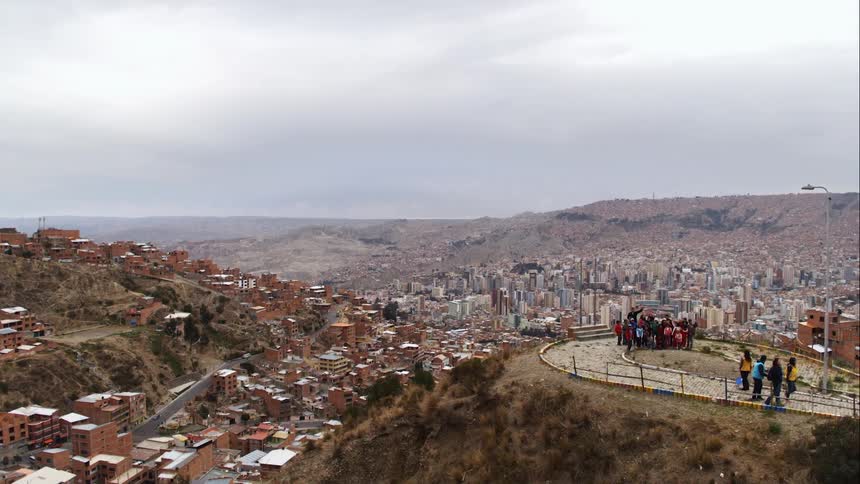 A group of people at the top of a hill walk along and look at the city skyline