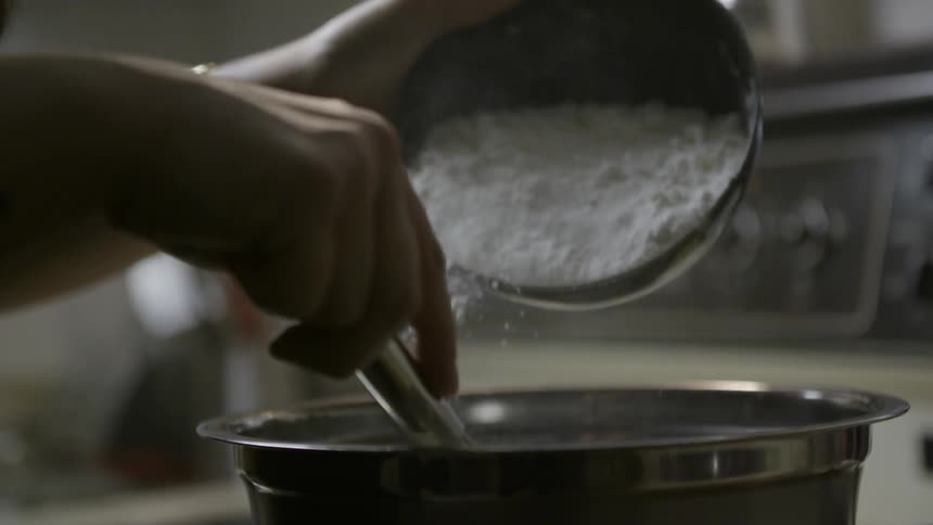 Person pouring flour into a mixing bowl