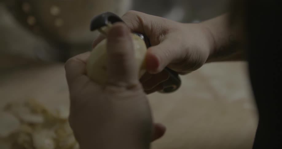 A person is peeling potatoes with a peeler