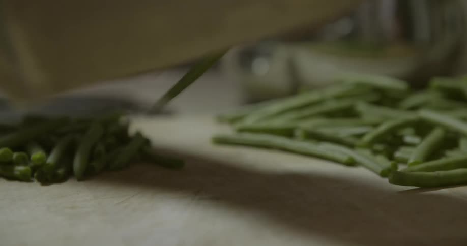 A person chops green beans