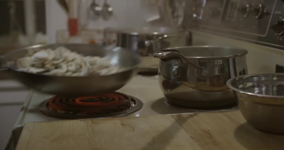 A person stirs a pan full of mushrooms