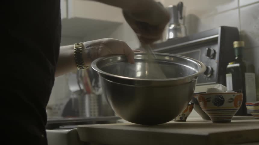 A person is using a whisk in a bowl
