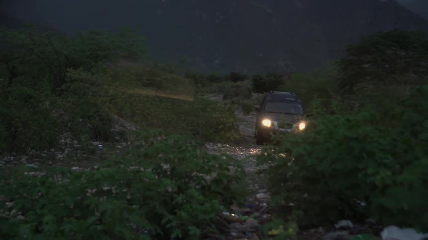 A truck drives over rocky terrain on a cloudy night