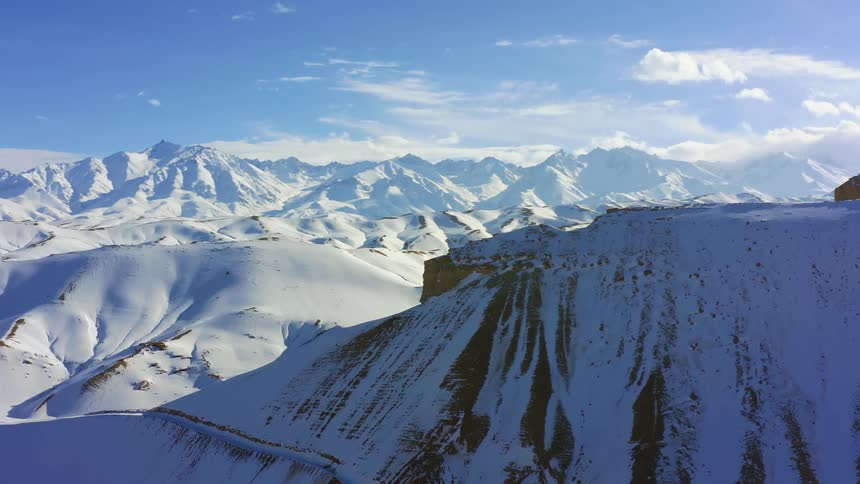 An aerial view of a mountain range in winter is displayed