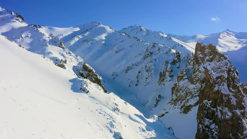 Snow covers mountain slopes near a valley