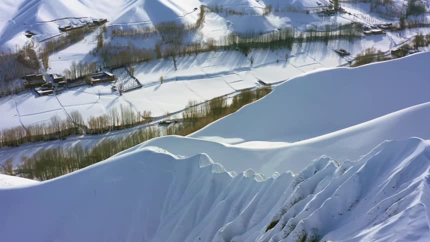 An aerial view of a snow covered hill with a road below