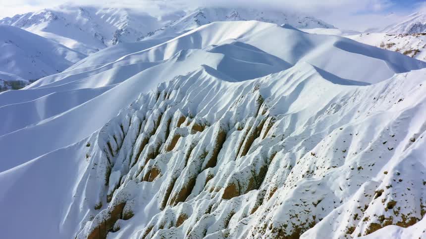 An aerial view of a snow covered mountain is displayed