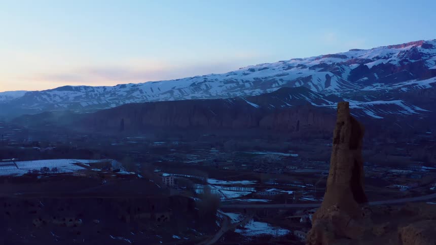 Sky over snowy mountain towering over town shows pink tint
