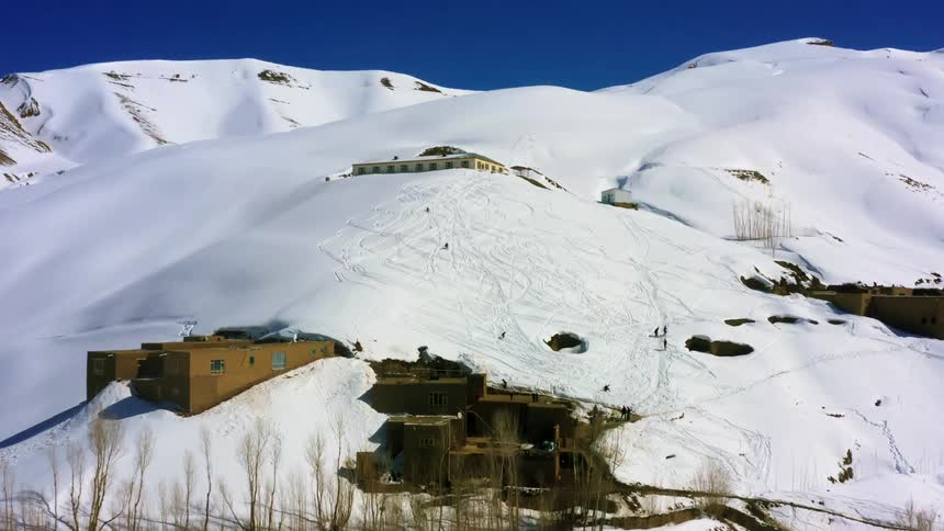 Several people ski at a mountain lodge during the winter