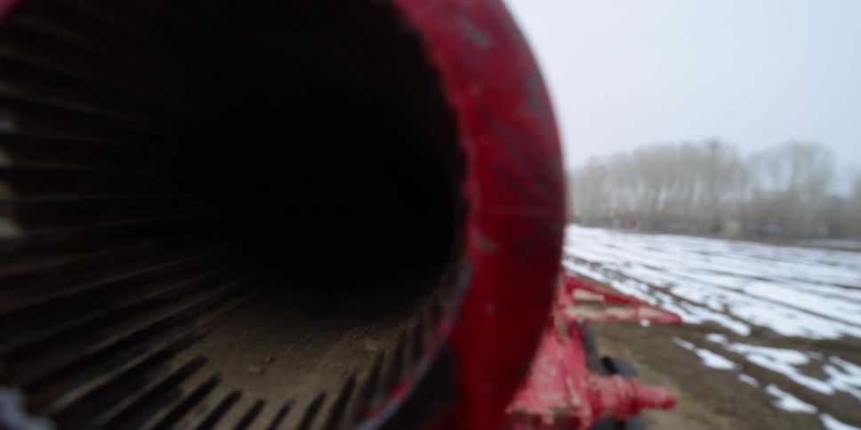 The main gun of an old tank in a snowy field on a winter day