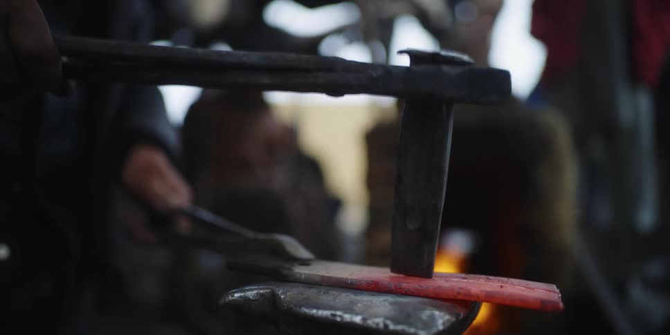 A blacksmith hammers a piece of hot metal