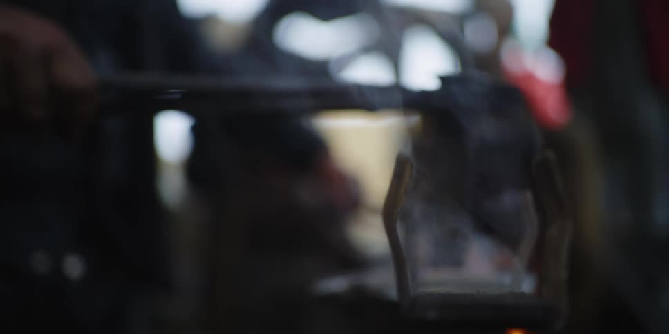 Men shaping steel over an open flame