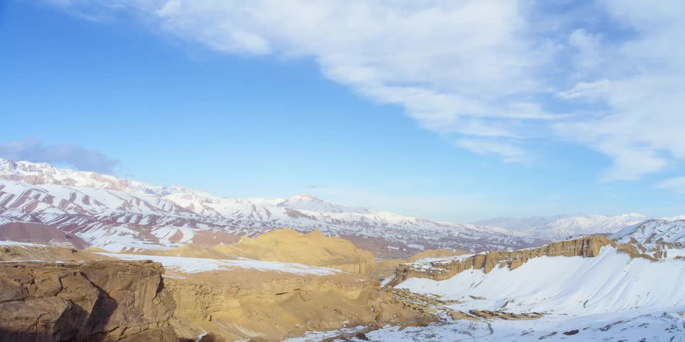 Snowy mountains landscape brightens as clouds move across blue sky