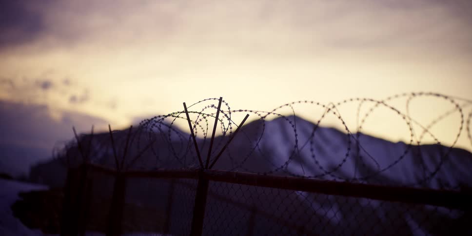 A barbed wire fence in the mountains on a cloudy evening