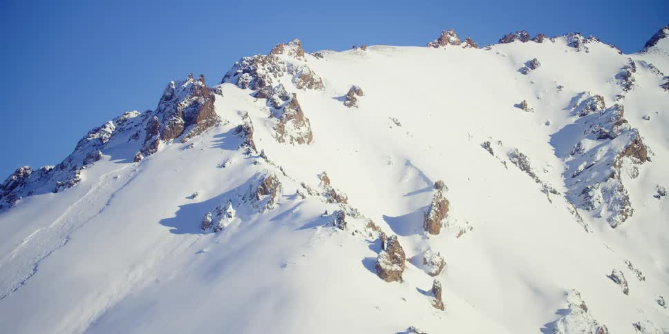 The sky is clear above the snow covered mountain