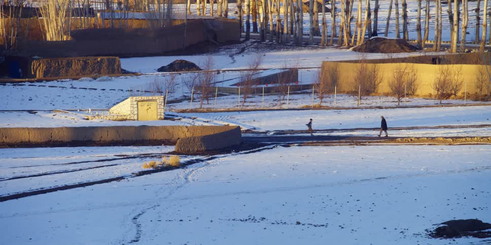 Pedestrians run in either direction along a small road on a winter day