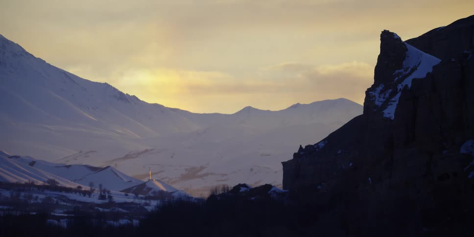 The sun is setting above the snowy mountains