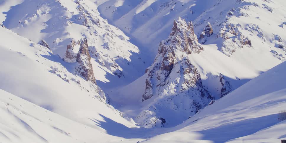 A narrow valley between snow covered mountain slopes on a sunny day