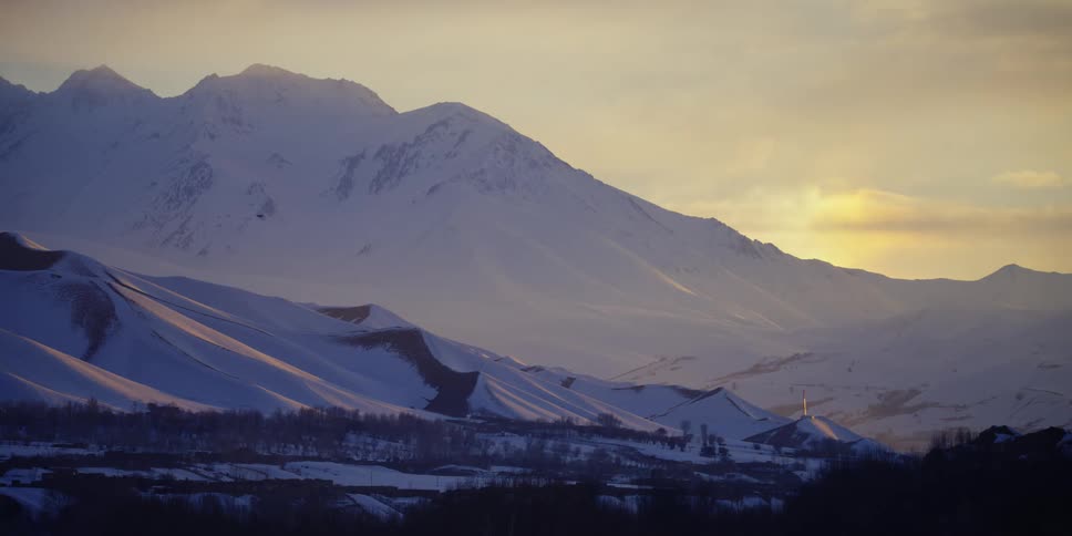 An aerial view of a snowy mountain at dusk is displayed