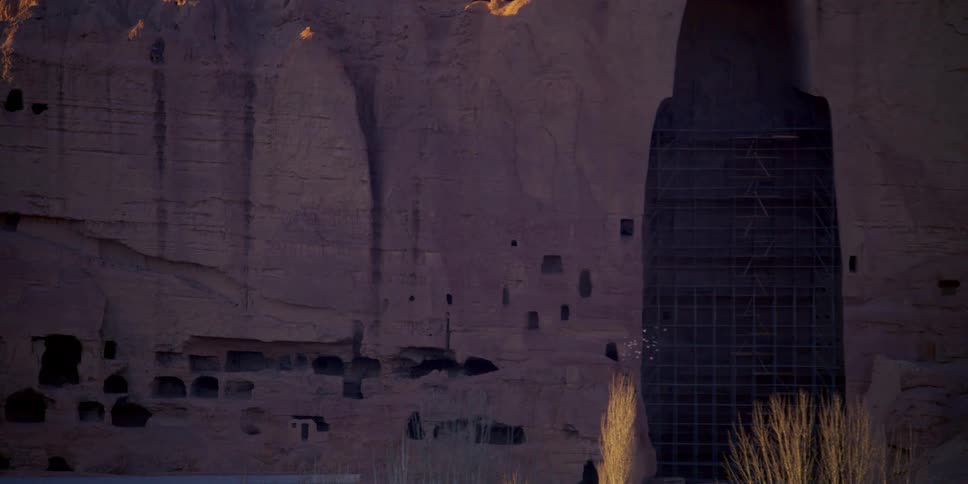 Flock flies across structure frame near cave dwellings