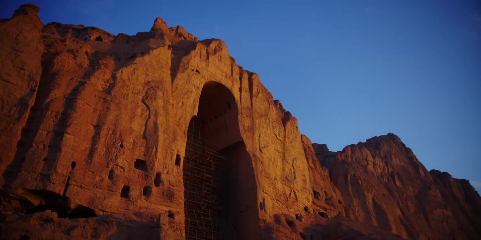 A giant cave entrance on the side of a mountain contains scaffolding