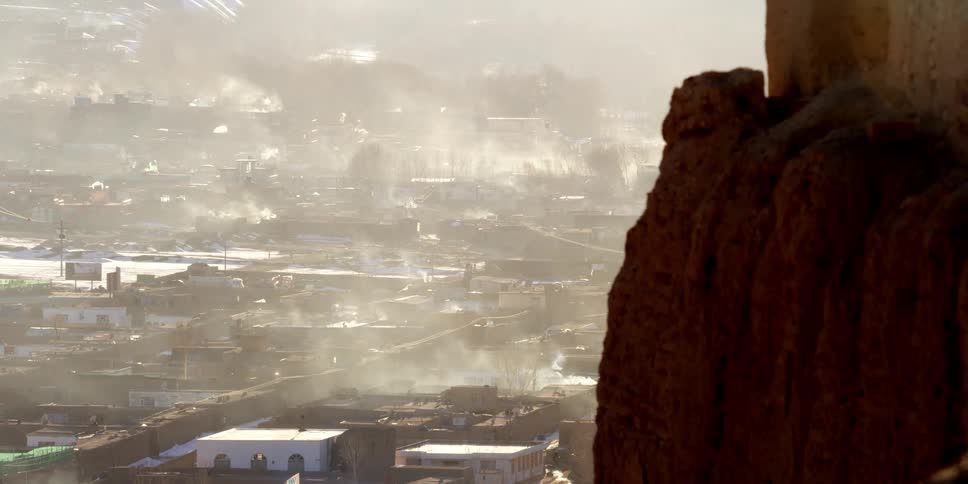 Heavy smoke billows from a building in a town in a developing country