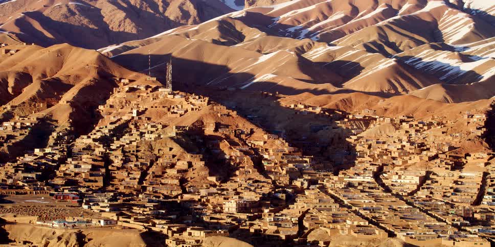 A village sits in a valley surrounded by sand dunes