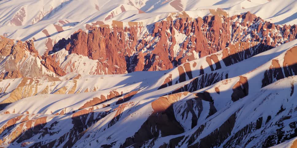 An aerial view of a mountain in winter is displayed
