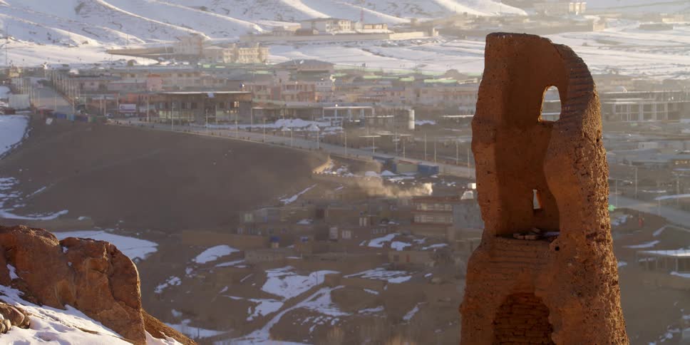 Steps are still visible in the ruins of a red rock structure overlooking a road and town below