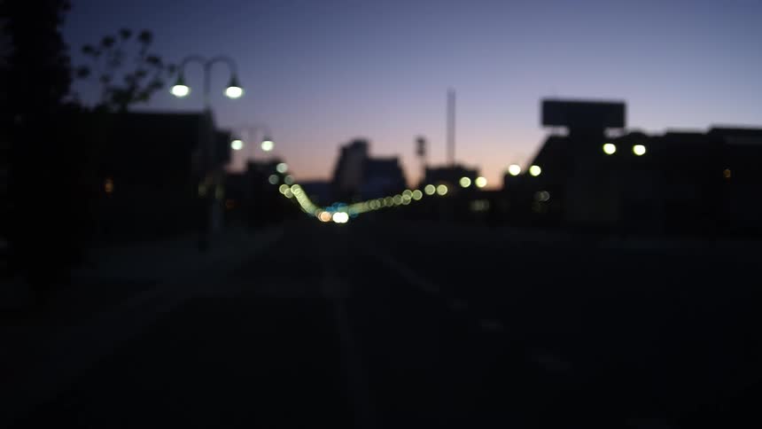 Headlights shine as cars drive down a city street at night
