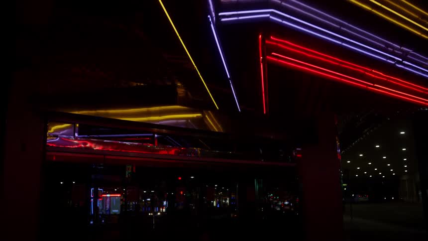 Neon lights in a city as cars drive past
