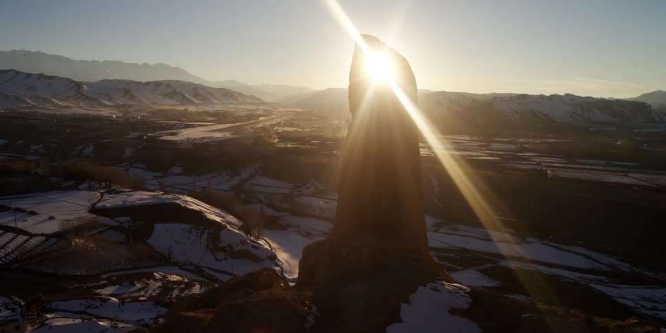 The sun shining through a tall rock formation in the wilderness
