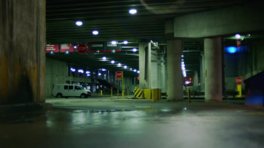 A white van parked in a parking garage at night