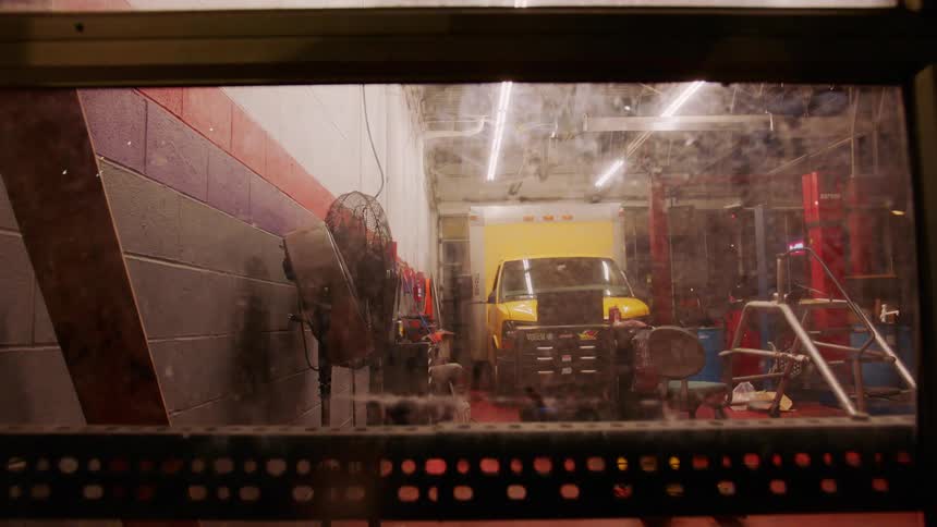 Yellow truck in the interior of an auto repair shop at night